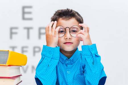 戴眼镜的学龄前男孩在模糊的字母背景上.照片