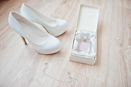 Elegant white wedding shoes with perfumes at bride morning. 