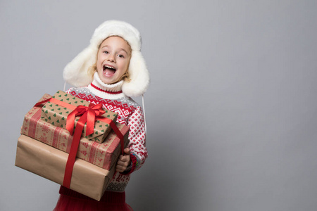 一个戴着蓬松帽子，手里拿着圣诞礼物的有趣的孩子。