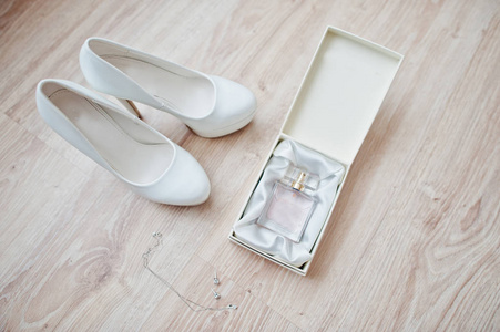 Elegant white wedding shoes with perfumes at bride morning. 