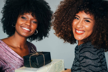 白色背景上两位迷人的美国黑人非洲妇女手持圣诞礼物的肖像。