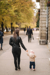 妈妈和女儿在公园散步。快乐的小女孩和妈妈在外面散步