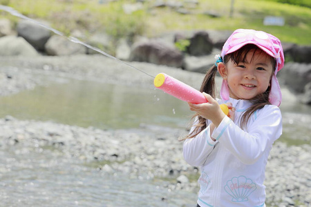 在河里玩水枪的日本女孩4岁