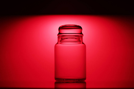 Empty glass jar on a red and black background