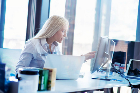 一位年轻商务女性在办公室使用笔记本电脑的肖像