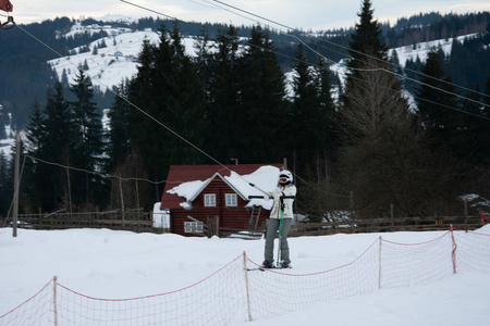 喀尔巴阡山脉冬季美丽的白色风景和传统的房屋。雪山和手动升降机。滑雪者和滑雪者骑着下坡进入村庄。