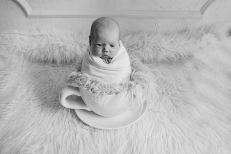 新生婴儿在一个大茶杯里。儿童概念，健康，试管婴儿，热饮，早餐