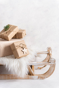 白色背景的乡村木制雪橇上的手工纸圣诞礼物。舒适的冬天。贺卡概念。复制空间