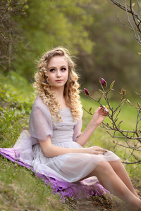 young beautiful girl in a light lilac dress in the garden where 