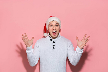 一个穿着白色毛衣和红色圣诞帽的男人非常兴奋地庆祝圣诞节和新年。