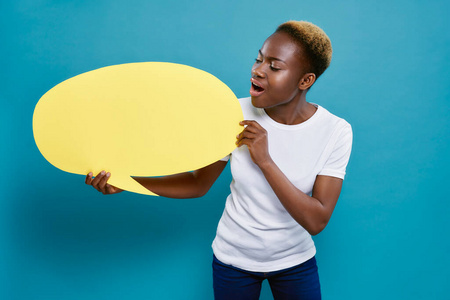 非洲妇女手持椭圆形的黄色讲话泡泡。