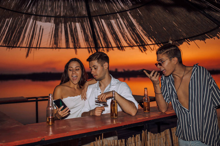 Young smiling couple having fun using a smartphone in the beach 