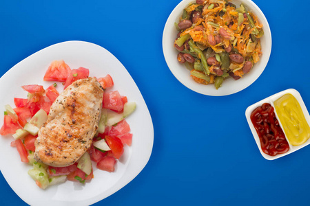 Grilled chicken breast with tomato salad, cucumbers and onions. 