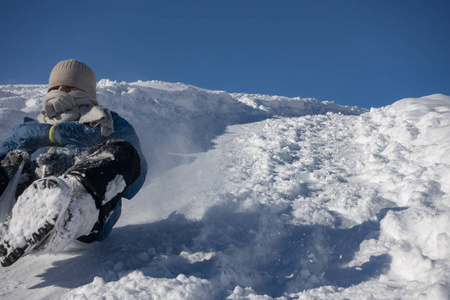 快乐的男孩滑下雪山在冬天的户外雪橇，sle
