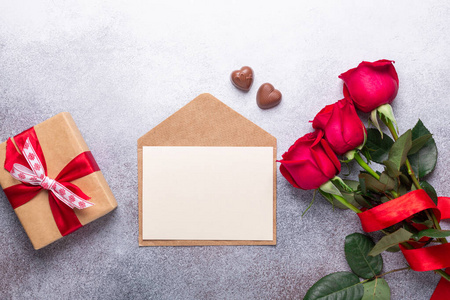 红玫瑰花束，信封，礼品盒，巧克力糖石头背景情人节贺卡