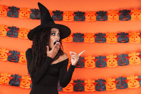 Image of witch woman in black halloween costume pointing finger 
