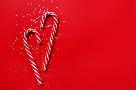 圣诞作文。红色背景上有星星五彩纸屑的糖果。冬天，新年的概念。平面布置，俯视图，复制空间