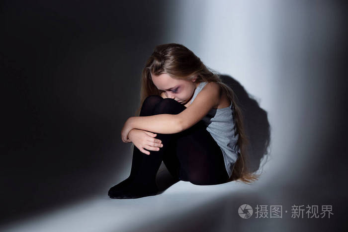 伤心又害怕的小女孩眼睛充血淤青坐在那里害怕