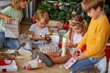  Children opening Xmas presents. Kids under Christmas tree with 