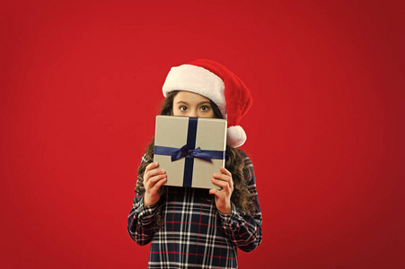 寒假快乐。小女孩。新年晚会。圣诞老人小子。戴着圣诞老人红帽子的小女孩。圣诞礼物。童年。圣诞购物。别害羞