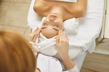 美容师给美女顾客面部按摩在美容院给一个漂亮女孩做面部按摩.照片