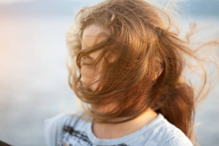 一幅美丽的金发年轻女子的肖像画,在海边刮风的天气里.