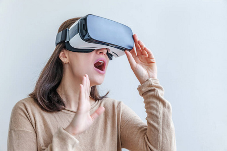 微笑年轻女子戴着虚拟现实虚拟现实眼镜头盔耳机白色背景。智能手机使用虚拟现实护目镜。技术，模拟，高科技，电子游戏概念。