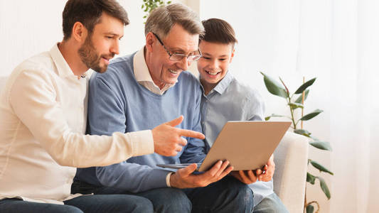 老人坐在屋内儿子和孙子之间用笔记本电脑