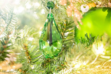 闪亮的圣诞绿水晶挂在松枝上，背景是节日