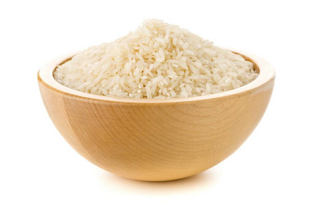 Heap of white uncooked, raw long grain rice in wooden bowl 