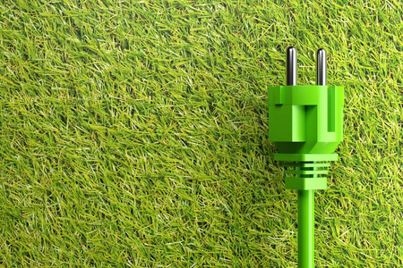 Green power cord with plug on grass background 