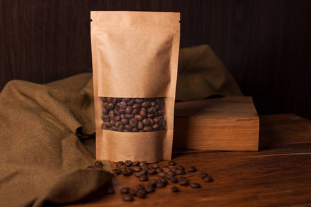 空白棕色牛皮纸袋装咖啡豆,透明窗户,木质背景.流行的茶叶包装照片