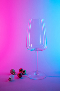 empty glass of wine with christmas tree ball decorations in pink