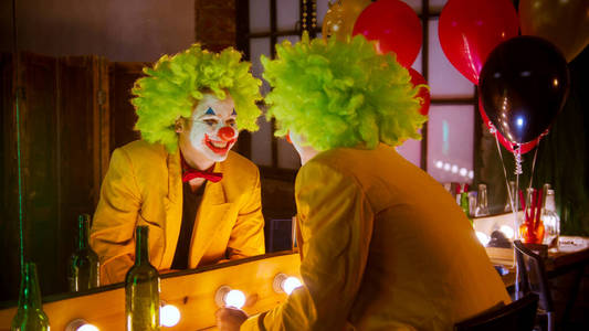 阴险的笑容小丑一个穿着盛装的疯子小丑对着镜子微笑照片