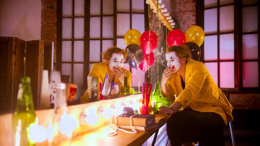 一个悲伤的小丑坐在镜子前抽烟照片