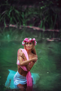 夏日绿色森林里，金发女孩浸在齐膝深的水中