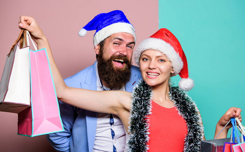 提前准备礼物。圣诞快乐。男人和女人在购物。圣诞购物。一对快乐的圣诞老人帽顶着纸袋。买礼物。新年快乐。家庭购物。加入庆祝活动