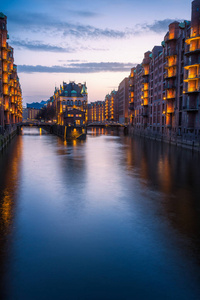 德国，欧洲，德国，汉堡市的老港口。历史著名的仓储区人工照明。水上城堡的宫殿倒映在河面上。垂直方向