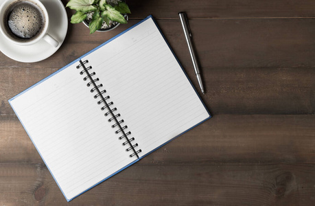 blank notebook and cup of black coffee on wood 