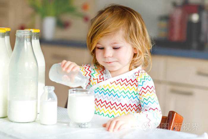 可爱的蹒跚学步的女孩早餐喝牛奶可爱的小女儿有很多