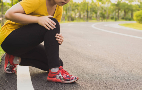 Knee Injuries. Young sport woman holding knee with her hands in 