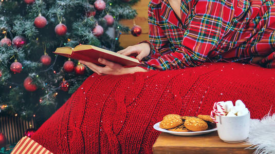 圣诞节早上，穿着睡衣的女孩拿着一本书。选择性聚焦。