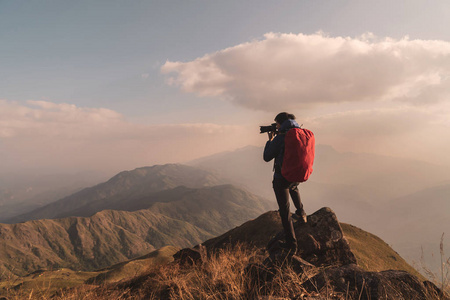 背着背包在山上拍照的年轻人旅行者