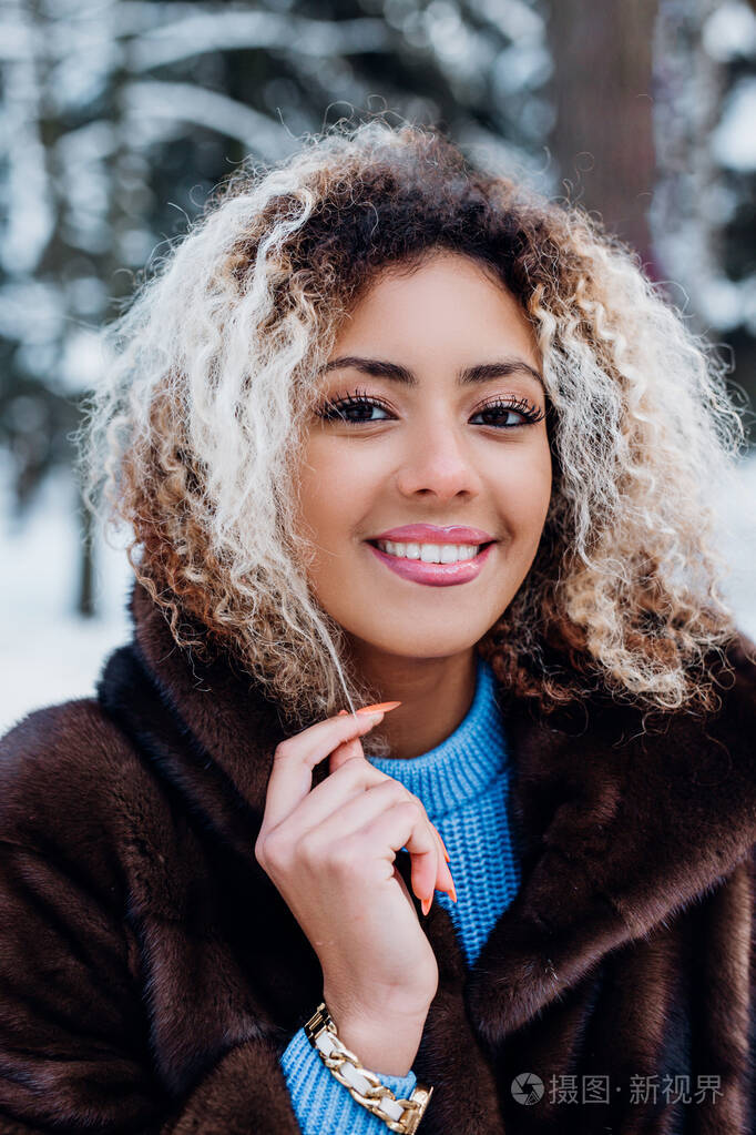 冬季公园里年轻微笑的美国黑人女孩的美丽写照