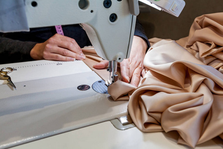 货架上的许多珍贵布料卷缝纫机和牛仔裤布料的一部分女工在缝纫车间