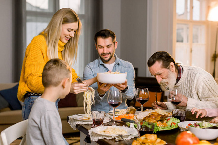 家庭休闲生活方式，感恩节晚餐理念。快乐的大家庭一起享用美味的晚餐，蔬菜沙拉，意大利面，火鸡