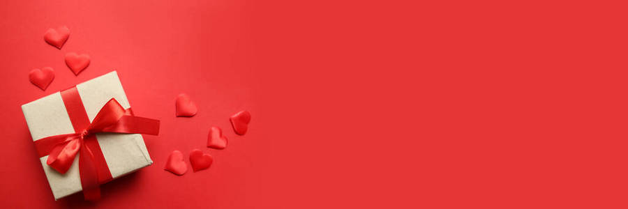 红色背景上有红色丝带和红色心形五彩纸屑的惊喜纸质礼物.情人节概念.