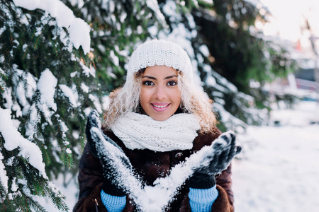 快乐的美国黑人妇女在冬季公园吹雪