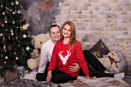 一对穿着舒适圣诞服的年轻情侣在圣诞树旁亲密拥抱