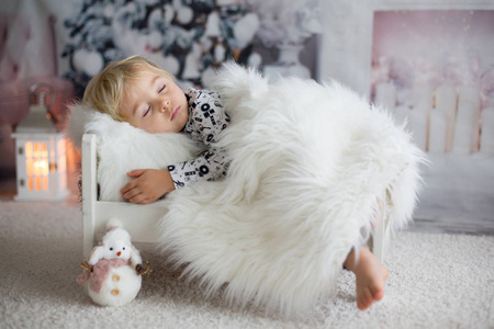 Beautiful toddler child, baby boy, sleeping on Christmas eve at 